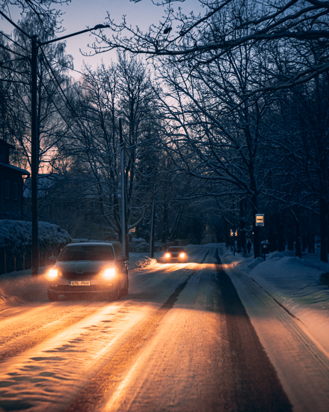 car headlights lighting up a snowy road in the dark